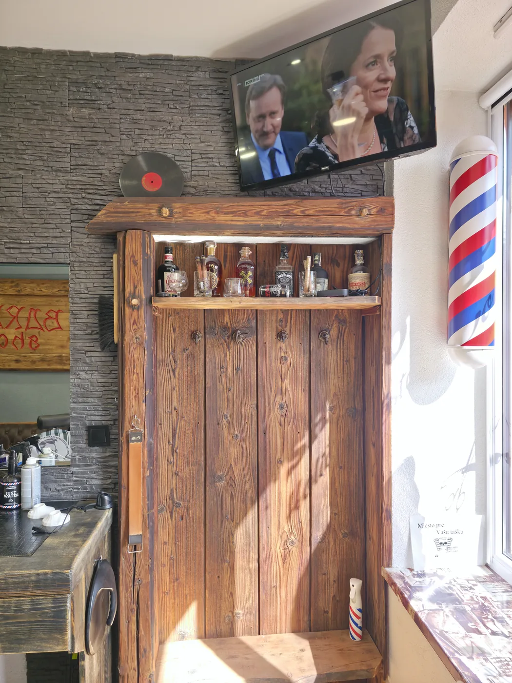 Drevená polica s produktmi a holičský stĺp v Barber Shop MF Kežmarok