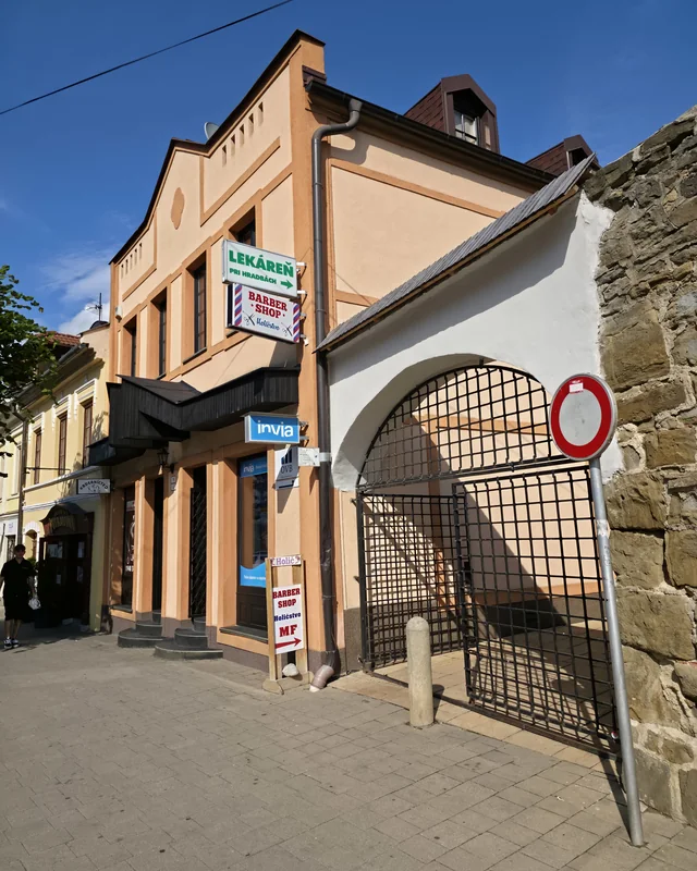 Budova Barber Shop MF na Hviezdoslavovej v Kežmarku — tabuľa Holičstvo MF a prechod pod bránou